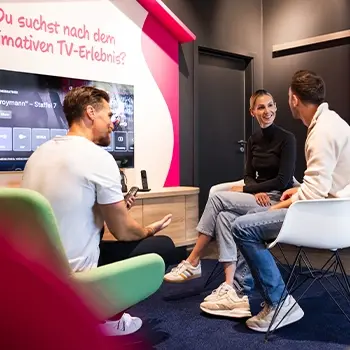 Drei Personen im Wohnzimmer testen interaktives TV-Streaming am Smart-TV
