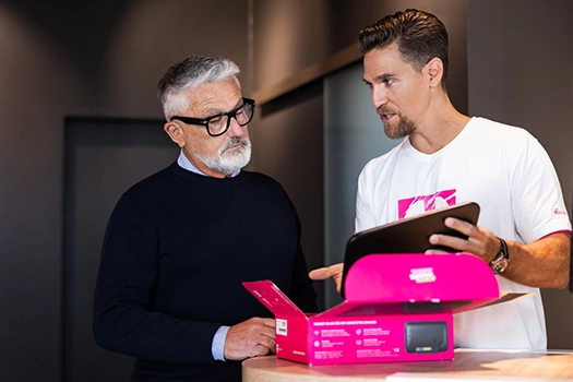 Zwei Männer besprechen Router-Setup, Techniker zeigt Tablet und Box im Büro