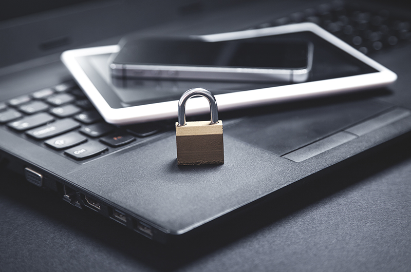 Vorhängeschloss auf Laptop mit Tablet, Symbol für IT-Sicherheit und Datenschutz